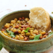 A bowl of lentils and beans with a slice of bread