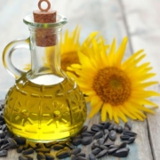 Sunflower seed oil in a decanter on a table next to sunflower blossoms and sunflower seeds