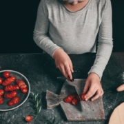 Mature woman dicing cherry tomatoes on a cutting board