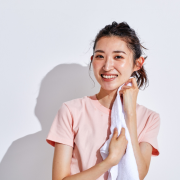 Woman in workout attire toweling off perspiration from her neck