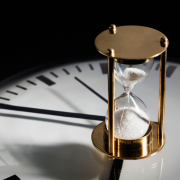 Hourglass placed atop the face of a clock