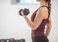 Woman in workout attire holding free weight in her left hand