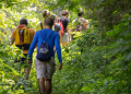 Group of hikers walk through wooded trail