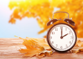Clock with autumnal leaves in the foreground and background