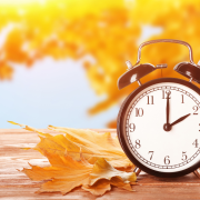 Clock with autumnal leaves in the foreground and background