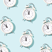 Old-fashioned white alarm clocks arranged in a pattern against a solid blue backdrop