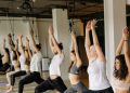 people standing with arms above heads in yoga studio