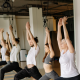 people standing with arms above heads in yoga studio