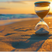 hourglass placed on a sandy beach with the ocean in the background