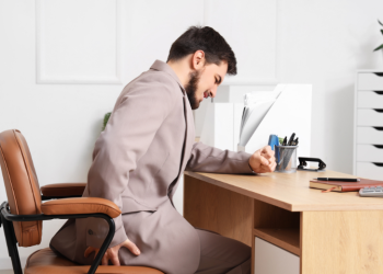 Man sitting at desk holding back in pain