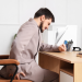 Man sitting at desk holding back in pain