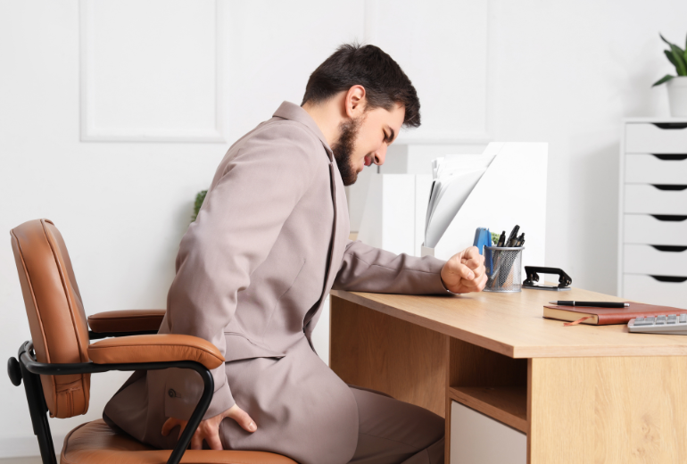 Man sitting at desk holding back in pain